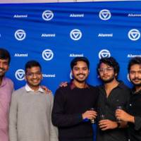 Large group of grads smile in front of GVSU Alumni backdrop
